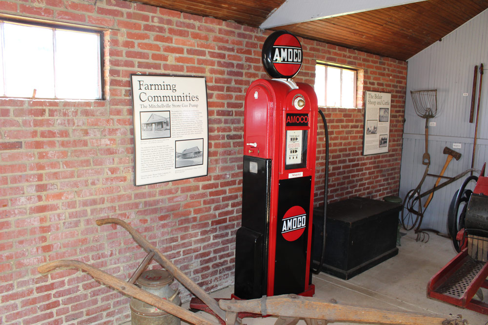 Restored Wayne Pump Company Amoco gasoline pump, red and black livery, ca. 1935, on display at the Belair Stable Museum alongside the Farming Communities interpretive sign. The pump formerly stood at the Mitchellville Store on Mitchellville Road.